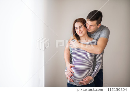 Pregnant woman and her partner, touching her belly. 115150804