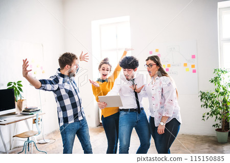 Young group of colleagues working on a new project together in a startup company office. Working in co-working space. 115150885