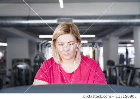 Overweight woman exercising on treadmill in gym. 115150903