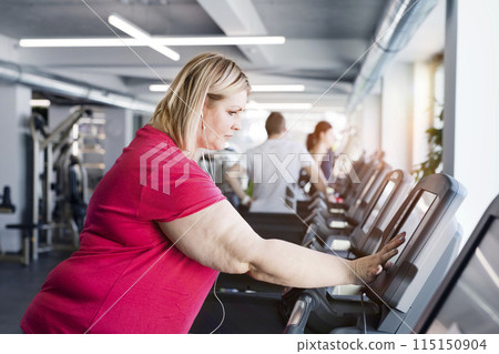 Overweight woman exercising on treadmill in gym. 115150904
