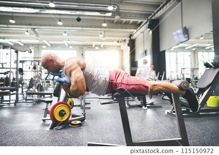 Strong man exercising in gym. Routine workout for physical and mental health. 115150972