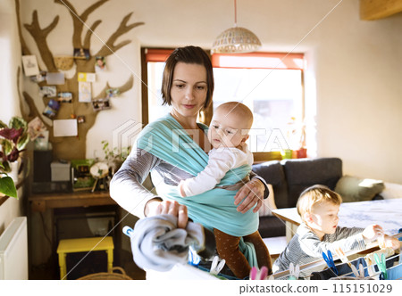 Young son helping mother with hosehold chores, hanging clothes on drying rack. Weekly chores, weekend activities. Young son helping mother with hosehold chores, hanging clothes on drying rack. Weekly chores, weekend activities. 115151029