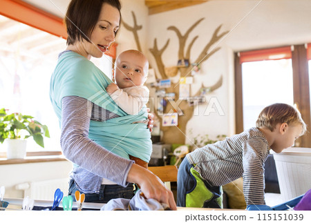 Young son helping mother with hosehold chores, hanging clothes on drying rack. Weekly chores, weekend activities. 115151039