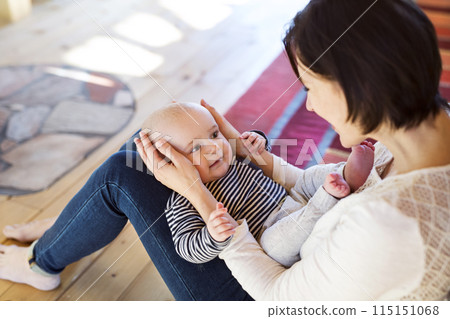 Mother playing with small baby, holding him on her knees. Unconditional paternal love, mother's Day concept. Mother playing with small baby, holding him on her knees. Unconditional paternal love, mother's Day concept. 115151068