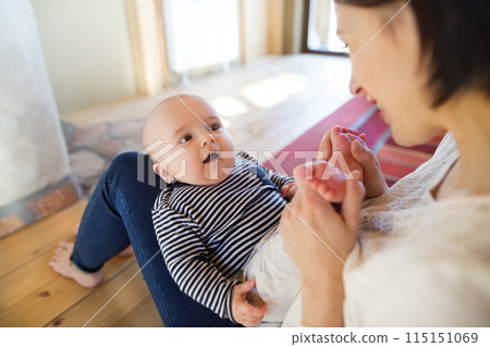 Mother playing with small baby, holding him on her knees. Unconditional paternal love, mother's Day concept. Mother playing with small baby, holding him on her knees. Unconditional paternal love, mother's Day concept. 115151069