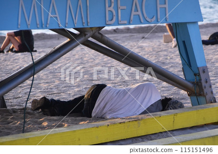 Homeless man sleeping on a beach in Miami 115151496