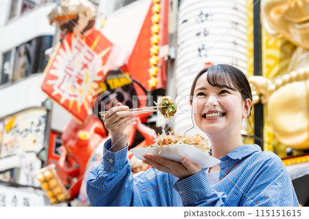 一位女士在大阪道頓堀吃著名的章魚燒 一位女士在大阪道頓堀吃著名的章魚燒 115151615