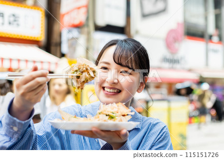 一位女士在大阪道頓堀吃著名的章魚燒 115151726