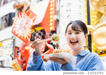 A woman eating the famous takoyaki in Dotonbori, Osaka A woman eating the famous takoyaki in Dotonbori, Osaka 115151753