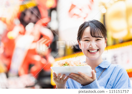 A woman eating the famous takoyaki in Dotonbori, Osaka A woman eating the famous takoyaki in Dotonbori, Osaka 115151757