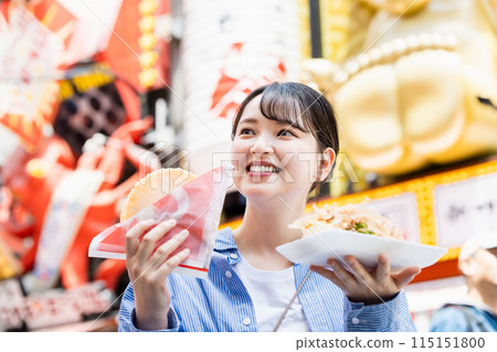A woman eating the famous takoyaki and takosen in Dotonbori, Osaka 115151800
