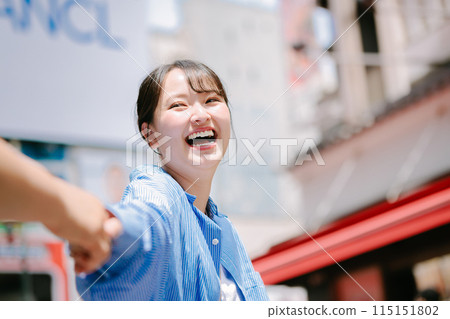 A woman holding her boyfriend's hand while sightseeing in Osaka 115151802