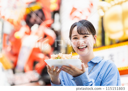 A woman eating the famous takoyaki in Dotonbori, Osaka 115151803