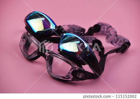 Swimming goggles resting against a vibrant pink background, offering a striking and colorful contrast. Swimming goggles resting against a vibrant pink background, offering a striking and colorful contrast. 115152002