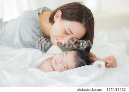 Baby sleeping next to mother 115153382