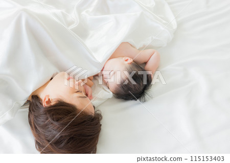 Baby sleeping next to mother 115153403