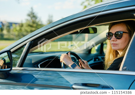 Woman wearing sunglasses is driving car Woman wearing sunglasses is driving car 115154386