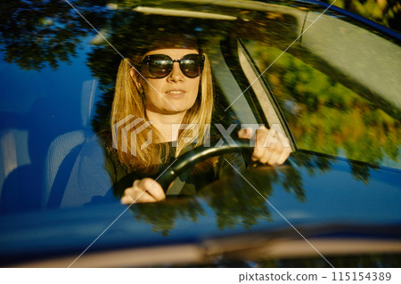 Happy woman is sitting in car. View through windshield 115154389