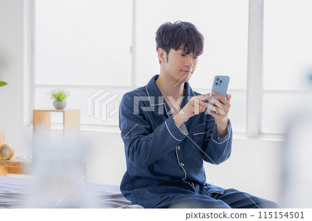 A man waking up in the morning and looking at his smartphone 115154501