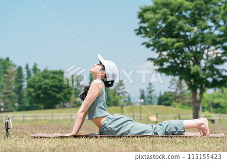 A woman who does yoga and muscle training using a smartphone app in the park (yoga mat) A woman who does yoga and muscle training using a smartphone app in the park (yoga mat) 115155423