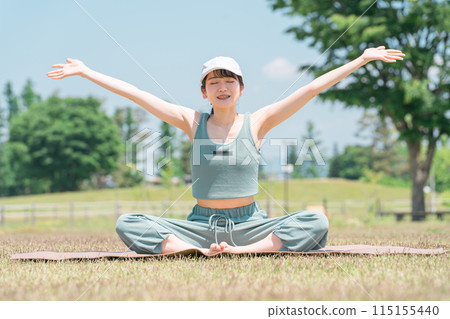 A woman doing yoga, stretching, deep breathing, and refreshing using a yoga mat in the park (sunny, weather) 115155440