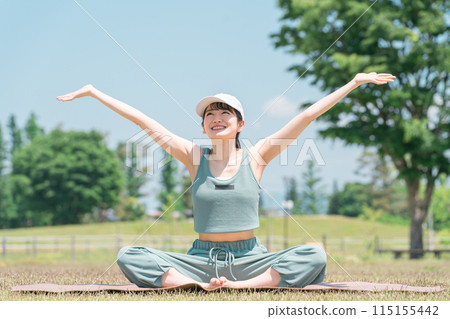 A woman doing yoga, stretching, deep breathing, and refreshing using a yoga mat in the park (sunny, weather) A woman doing yoga, stretching, deep breathing, and refreshing using a yoga mat in the park (sunny, weather) 115155442