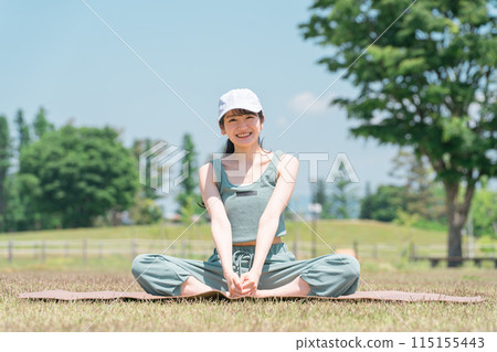 A woman doing yoga, stretching and exercising using a yoga mat in the park 115155443