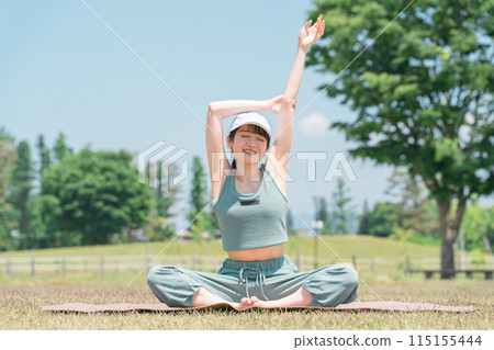 A woman doing yoga, stretching and exercising using a yoga mat in the park A woman doing yoga, stretching and exercising using a yoga mat in the park 115155444