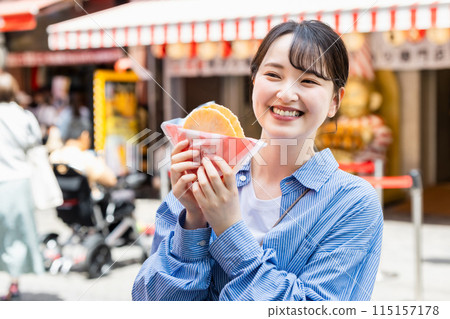 一位女士在大阪道頓堀吃著名的章魚線 115157178