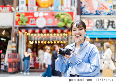 A camera girl taking pictures of the streets of Osaka 115157294