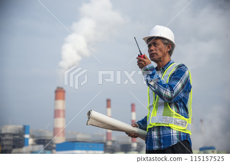 Senior Electrician engineer man hand holding red Walkie talkie communicate wear White hardhat at Power stations manufacturing electrical plant. Technician worker blue hard hat helmet Engineer industry 115157525