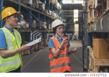 Warehouse management team check stock inventory. Asian men women worker use bar code scaner scan goods shelf writing checklist on clipboard. Teamwork logistics staff counting products store inventory 115157712
