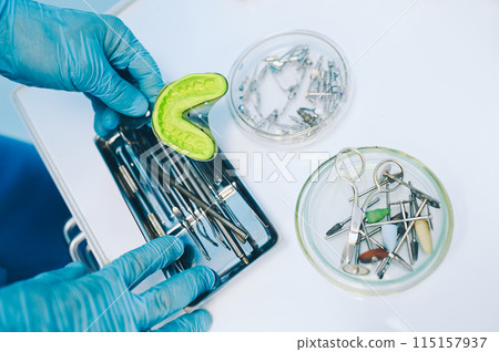 Different professional dental equipment, instruments and tools in a dentists stomatology office clinic on a white background. Silicone cast of the jaw. 115157937