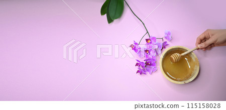 Set of depilation and beauty on pink background concept - sugar paste or hair removal waxing melted paste, orchid and female hands. Sugar paste or honey in a wooden bowl with a special dipper stick. Set of depilation and beauty on pink background concept - sugar paste or hair removal waxing melted paste, orchid and female hands. Sugar paste or honey in a wooden bowl with a special dipper stick. 115158028