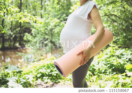 Unrecognizable young pregnant woman preparing to do yoga exercising with pink yoga mat. Active future mother sport lifestyle. Healthy pregnancy concept Unrecognizable young pregnant woman preparing to do yoga exercising with pink yoga mat. Active future mother sport lifestyle. Healthy pregnancy concept 115158067
