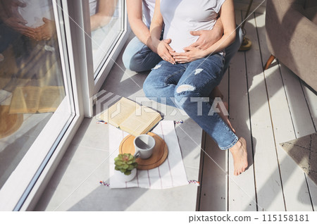 Pregnancy concept - happy man hugging his beautiful pregnant wife at home. Future parents waiting unborn baby. Love, relationship, birth, happy family concept - young lovely married couple 115158181