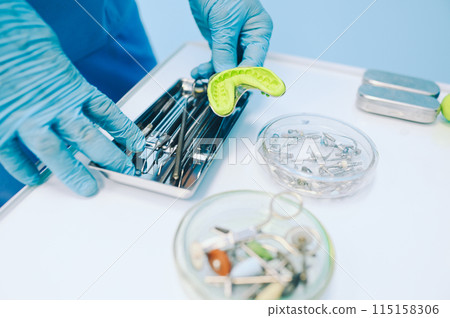Different professional dental equipment, instruments and tools in a dentists stomatology office clinic on a white background. Silicone cast of the jaw. Different professional dental equipment, instruments and tools in a dentists stomatology office clinic on a white background. Silicone cast of the jaw. 115158306