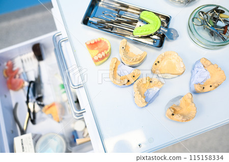Different professional dental equipment, instruments and tools in a dentists stomatology office clinic on a white background. Silicone cast of the jaw. 115158334