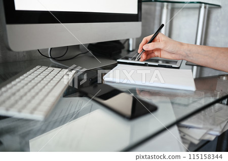 Unrecognizable woman hands writing in empty mock up notebook and computer. Freelancer using smart phone and laptop at home during quarantine. Unrecognizable woman hands writing in empty mock up notebook and computer. Freelancer using smart phone and laptop at home during quarantine. 115158344
