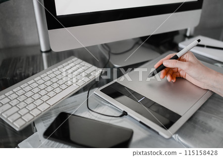 Workplace of photographer or graphic designer. Creative designer hands working on laptop with graphic tablet. 115158428