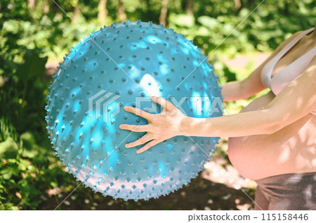 Beautiful young pregnant woman doing yoga exercising with fitness pilates ball in park outdoor. Standing and holding with both hands. Active future mother sport lifestyle. Healthy pregnancy concept Beautiful young pregnant woman doing yoga exercising with fitness pilates ball in park outdoor. Standing and holding with both hands. Active future mother sport lifestyle. Healthy pregnancy concept 115158446
