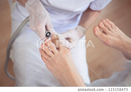 Hardware medical pedicure with nail file drill apparatus. Patient on pedicure treatment with pediatrician chiropodist. Foot peeling treatment at spa with a special device. Clinic of Podiatry Podology 115158473