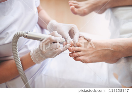 Hardware medical pedicure with nail file drill apparatus. Patient on pedicure treatment with pediatrician chiropodist. Foot peeling treatment at spa with a special device. Clinic of Podiatry Podology 115158547