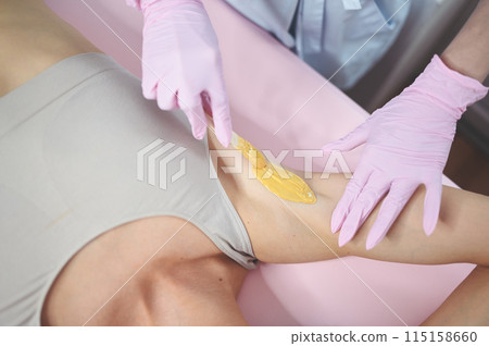 Waxing epilation and cosmetology in beauty salon. Hair removal procedure. Wax depilation, cosmetology, spa, hair removal concept. Beautiful smiling young woman getting hair removing on underarm 115158660