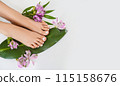 Beautiful perfect female skin legs feet top view with tropical flowers and green palm leaf. Nail polish, care and clean, spa pedicure treatment in white. Concept on background isolated. Copy space 115158676