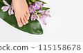 Beautiful perfect female skin legs feet top view with tropical flowers and green palm leaf. Nail polish, care and clean, spa pedicure treatment in white. Concept on background isolated. Copy space 115158678