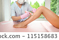Woman with long tanned perfect legs and smooth skin having wax stripe depilation hair removal procedure on legs in beauty salon. Beautician in blue robe, pink gloves. Body care, epilation spa concept 115158683