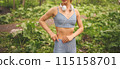 Young unrecognizable beautiful slim fit girl in blue sportswear with big white headphones doing sports and fitness in the summer park outside. Girl with perfect body doing yoga or exercises 115158701