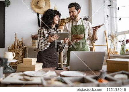 Two Caucasian workers in uniform doing inventory together at decor shop. 115158946