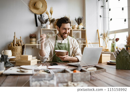 Caucasian man potter happy with online sale of bowl on Internet. Caucasian man potter happy with online sale of bowl on Internet. 115158992